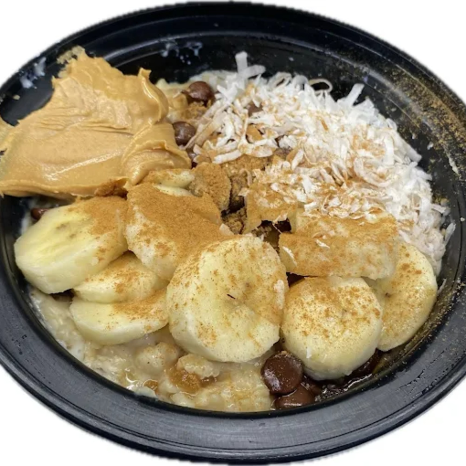 Oatmeal topped with sliced bananas, peanut butter, shredded coconut, chocolate chips, and cinnamon.